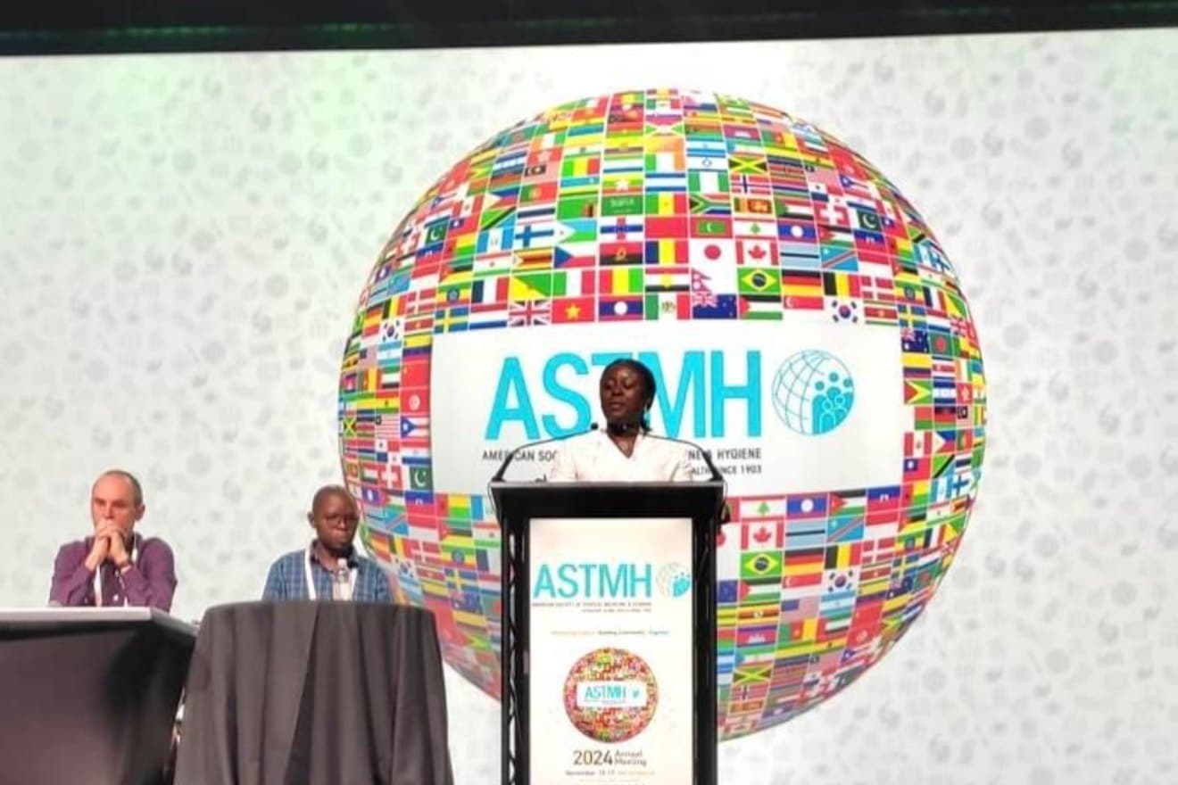 Rosine Z. Wolie at the ASTMH 2024 lectern, in front of the globe of flags