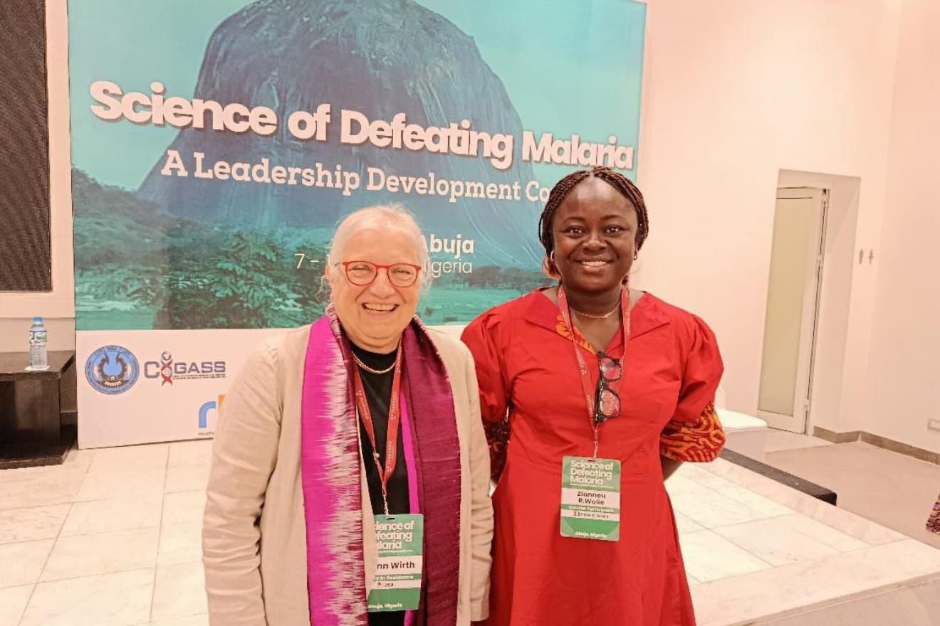 Rosine Z. Wolie with a fellow participant in front of the Science of Defeating Malaria banner